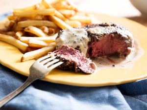 A plate of steak au poivre with french fries.