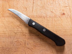 a tourné knife on a wooden cutting board