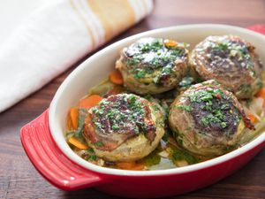 Closeup of old fashioned artichokes barigoule with mushrooms, served in an enameled casserole dish.