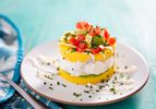 Layered dish of yellow mashed potatoes and tuna salad topped with diced tomatoes and avocados