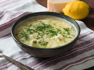 A bowl of stracciatella soup resting on a striped dishcloth.