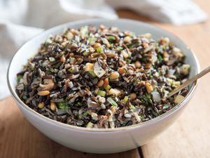 A large serving bowl containing wild rice salad with mushrooms, celery root, and pine nuts.