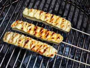 Grilled Brazilian cheese skewers on a grill grate, getting nicely browned.