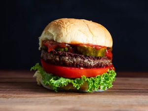 A burger with lettuce, tomato, pickles, and a vegan patty.