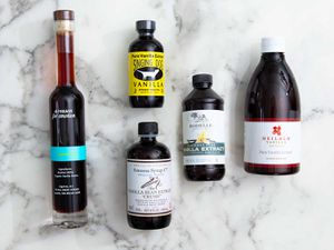 An assortment of vanilla extract bottles on a marble background.