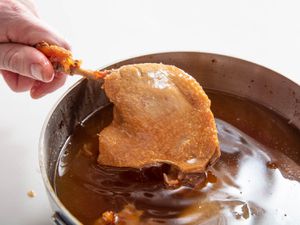 Duck confit being pulled out of a pot