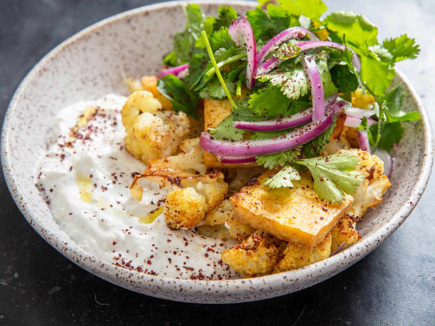 bowl of sheet pan cauliflower and tofu with yogurt sauce