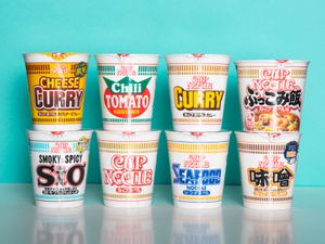 8 varieties of Cup Noodle instant ramen are displayed against a light blue background.