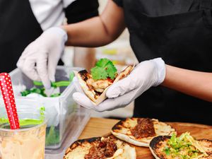 hands wearing gloves prepare tacos