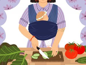 An illustration of a woman with a baby strapped to her body in a carrier while she slices vegetables.