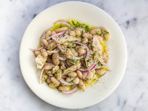 White bean, tuna, and pickled red onion salad on a white plate