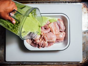 Mint-yogurt marinade being poured over boneless skinless chicken thighs