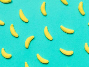 Closeup of banana-shaped candies arranged on a turquoise background.