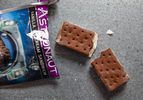 Closeup of an opened package containing an astronaut ice cream sandwich. The sandwich lies nearby, broken in half.