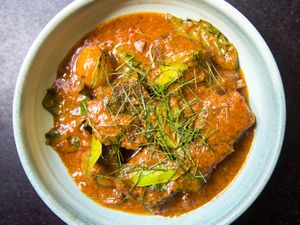 Overhead shot of a dish of Thai Panang Curry Beef Short Ribs garnished with thinly sliced lime leaves