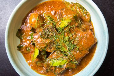 Overhead shot of a dish of Thai Panang Curry Beef Short Ribs garnished with thinly sliced lime leaves