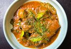 Overhead shot of a dish of Thai Panang Curry Beef Short Ribs garnished with thinly sliced lime leaves