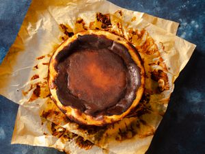 Overhead of a Basque cheesecake resting on two pieces of parchment paper