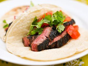 Sliced skirt steak tacos with tomatoes and cilantro on a plate