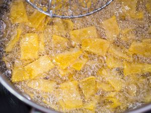 Overhead view of tortilla strips frying in oil.