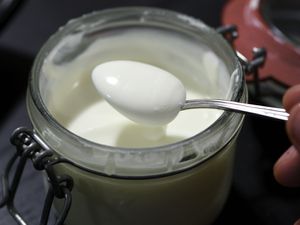 A jar of homemade crème fraîche, with a spoon dipping in it.