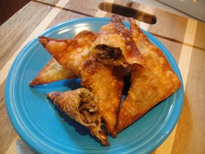 A plate of Somali sambusas, with one broken open to show the beef filling. 