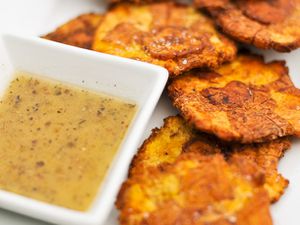 A small dish of mojo sauce next to some tostones. 