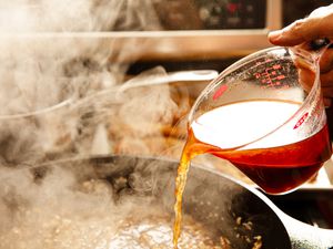 Chicken stock being poured into a pan.