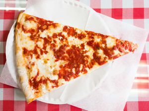 A slice of New York pizza (from Sac's Place) on a paper plate. 