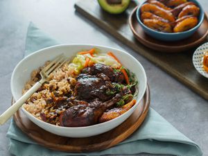 Bowl of brown stew chicken and rice and peas