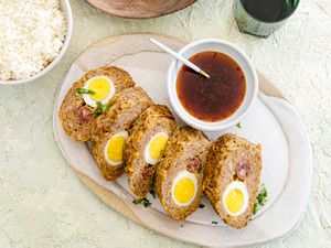 Embutido cut into 5 pieces and plated next to sauce and a serving of rice