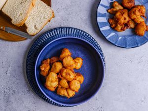 Akara on a deep blue bowl with a serving of white bread and a serving plate 