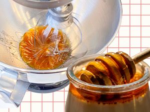 A stand mixer whipping honey next to a jar of honey. 