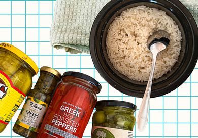 basmati rice in a bowl with a silver spoon accompanied by jars of brined vegetables