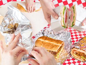 A sandwich of different hands wrapping sandwiches.