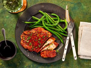 Pork chops on a plate with green beans.