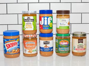 Jars of crunchy peanut butter lined up on a counter.