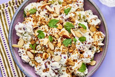 Grape Salad with fresh mint leaves on a purple surface, with a purple striped towel.