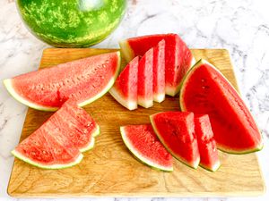 Sliced watermelon sitting on a wooden cutting board. 