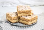 Stack of NJ Crumb buns on a plate, with a striped napkin and a white tabletop 