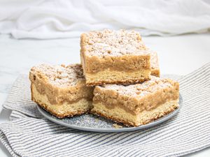 Stack of NJ Crumb buns on a plate, with a striped napkin and a white tabletop 