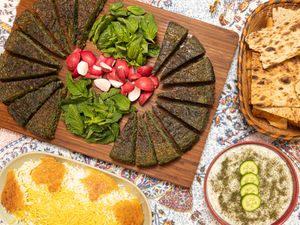 Platter of sliced kookoo, flatbread, and rice on a floral tablecloth