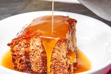 Side view of pouring sauce on sticky toffee pudding 