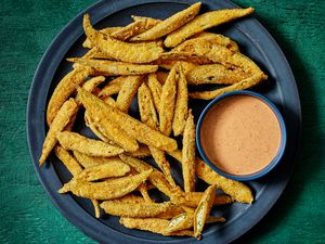 Dark blue plate with fried okra and a bowl of comeback sauce, on a deep green surface