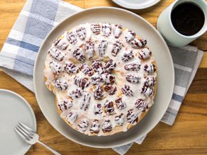 Yeasted coffee cake on wooden table with blue and white plaid napkin, cup of coffee and small plate