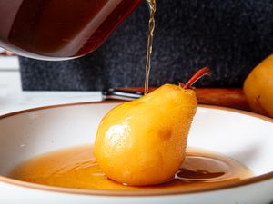 Pouring sauce over poached pear