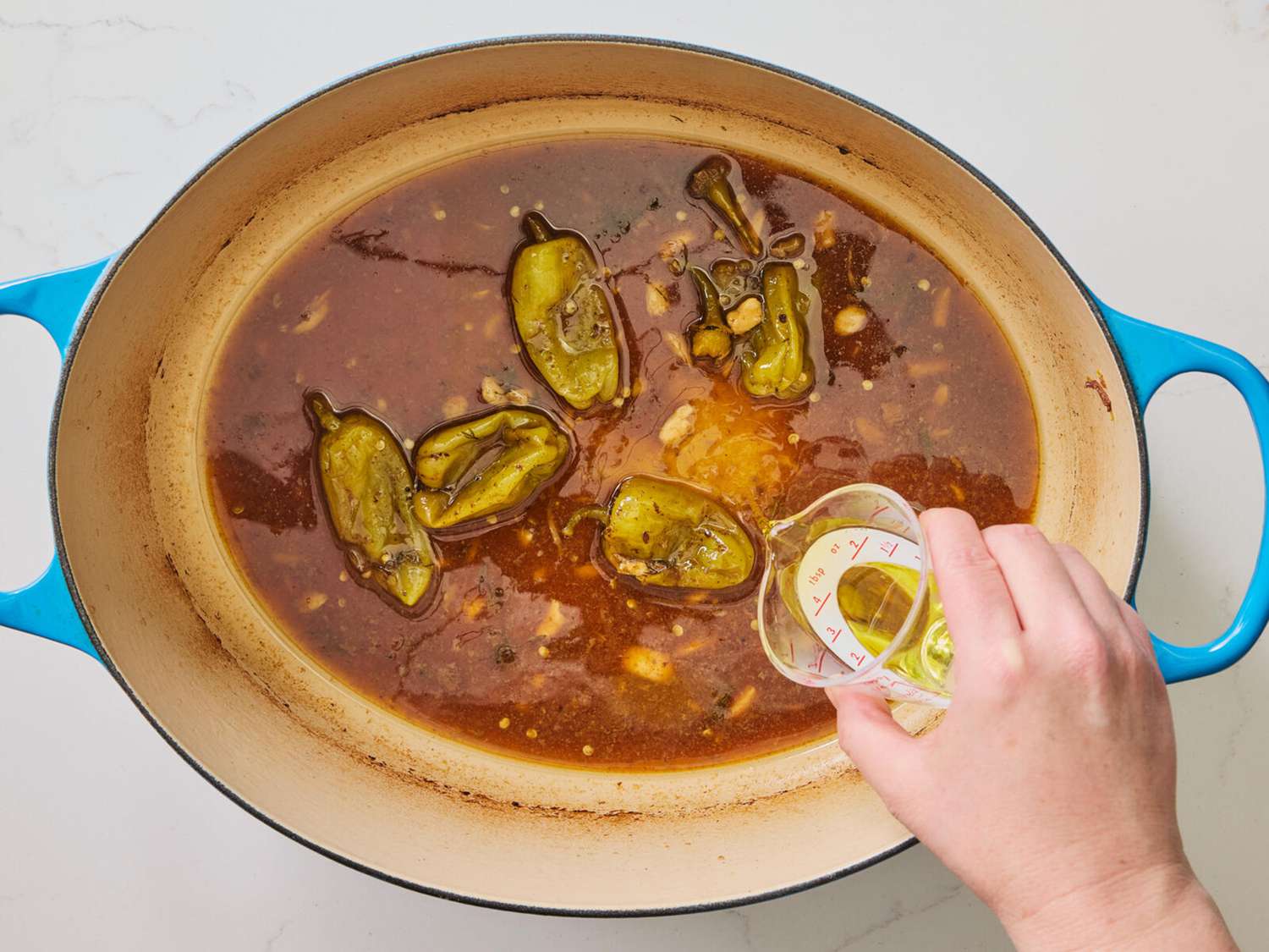 Pouring pepperoncini liquid to stew 