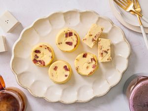 Overhead off egg bites on a scalloped platter with coffee, smaller plates and gold forks to the side