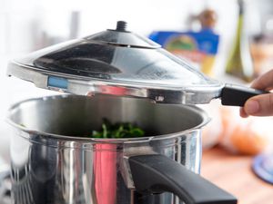 Lifting off a lid of a pressure cooker.