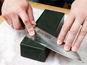 a knife being sharpened on a lower grit whetstone